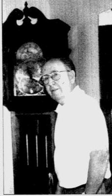 John Noll, in retirement, at Ocala, Fl, standing next to a Grandfather clock he built.