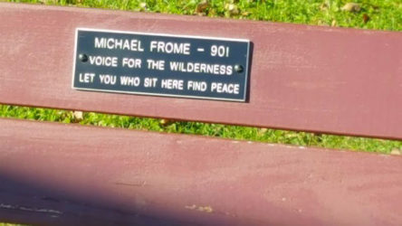 Red-colored park bench with plaque celebrating Michael Frome's 90th birthday.