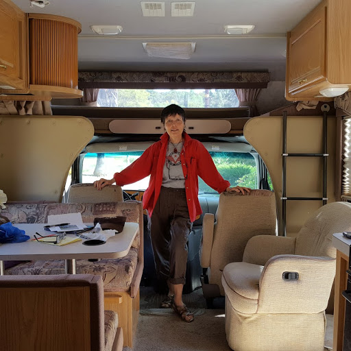 Gaye Lyn standing inside her 24' RV, surrounded by research materials and computer.