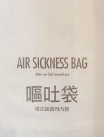 The writing on a small white paper sack says "Air Sickness Bag. After use fold toward you."