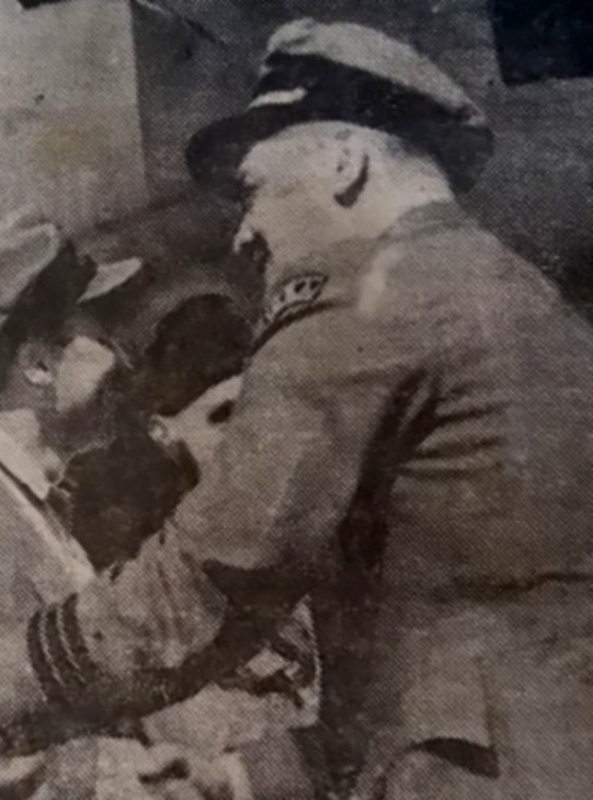 Photo of Captain William Jakeman shaking hands during Prague arrival. Three stripes on left sleeve of his uniform indicate Captain rank.